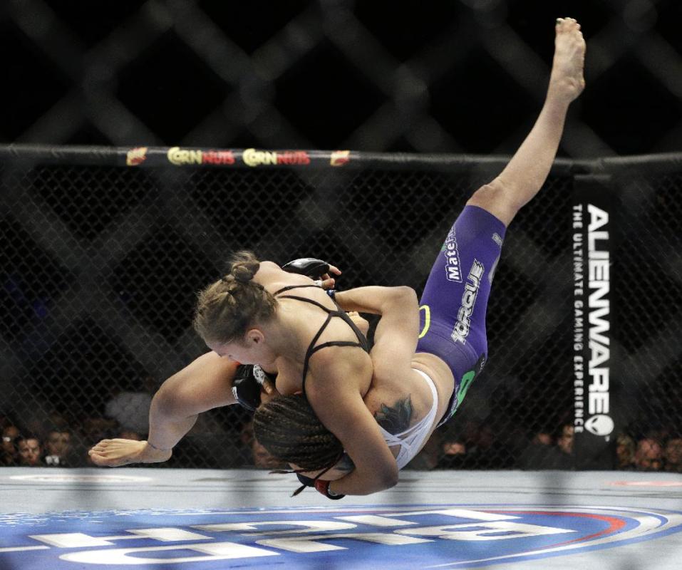 Ronda Rousey, left, takes down Alexis Davis during their women&#39;s mixed martial arts bantamweight title bout at UFC 175 on Saturday, July 5, 2014, in Las Vegas