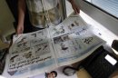 Egyptian cartoonist Khalid Abdul-Ati holds a copy of the Egyptian Al Watan daily newspaper with a two-page spread of cartoons with a headline in Arabic that reads 