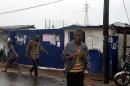 People walk under the rain by a school that was used as an isolation ward for Ebola patients on August 17, 2014 in the West Point district of Monrovia