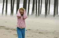 Molly White, 9, from Frankford, Del., covers her head as she is pelted by blowing sand on the beach, as Hurricane Sandy bears down on the East Coast, Sunday, Oct. 28, 2012, in Ocean City, Md. (AP Photo/Alex Brandon)