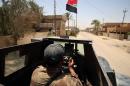 A member of the Iraqi counter-terrorism forces drives an armed vehicle flying his national flag in Fallujah
