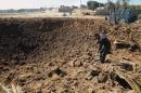 A Palestinian man digs in a crater after an Israeli air strike overnight, near the Nusseirat refugee camp in the centre of the Gaza Strip, on February 11, 2014