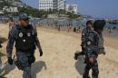 Federal police officer patrol Caleta beach crowded with local residents and tourists in Acapulco, Mexico, Friday, May 13, 2016. The city of Acapulco and Guerrero state in general have experienced a wave of violence attributed to warring drug gangs. On Saturday Mexican authorities say three men were gunned down, in a tourist-hotel quarter of the Pacific resort city. (AP Photo/Enric Marti)