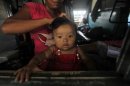 A woman from India's northeastern states ties the hair of her child while sitting inside the train bound for the Assam state at a railway station in Kolkata