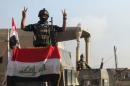A member of the Iraqi security forces gestures at a government complex in the city of Ramadi