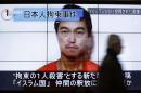 Man walks past screens displaying TV news programme showing image of Goto, one of two Japanese citizens taken captive by Islamic State militants, on a street in Tokyo