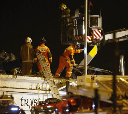 Rescue workers examine the wreckage of a police helicopter which crashed onto the roof of a pub in Glasgow