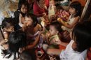 Liza Cabiya-an, a 39-year-old housewife with 14 children aged between 22 and 11 months, eats bread dipped in coffee, with some of her children at a cramped shanty in Manila