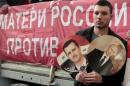 A participant hold images of Russian President Putin and Syrian President al-Assad during an anti-war protest organised by the Communist party near the U.S. embassy in Moscow