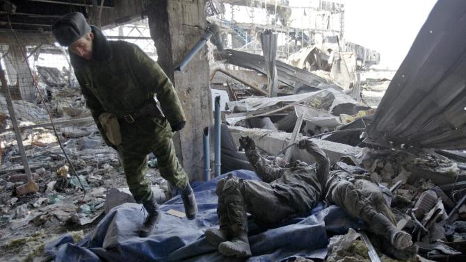 A Russia-backed separatist walks away from the bodies of Ukrainian servicemen retrieved from the rubble of the airport building outside Donetsk, Ukraine, Wednesday, Feb. 25, 2015. Ukrainian troops held captive in the separatist stronghold of Donetsk began digging through the rubble Wednesday to retrieve the bodies of fellow soldiers killed last month in a bitter battle for the city's airport. (AP Photo/Vadim Ghirda)