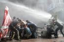 Protesters protect themselves as Turkish riot police fire water cannons to disperse a demonstration in Istanbul's Gazi district, on July 26, 2015