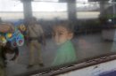 Child from India's northeastern state sits inside air-conditioned carriage while security personnel is reflected on windowpane at railway station in Kolkata