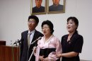 North Korean Pak Jong Suk, center, sings a Korean song titled ìMy Unforgettable Pathî with her son and daughter-in-law while standing under portraits of former North Korean leaders Kim Il Sung, left, and Kim Jong Il after speaking to reporters at the Peopleís Palace of Culture in Pyongyang, North Korea, on Thursday, June 28, 2012. Pak told local and foreign reporters she was tricked into defecting to South Korea by agents who offered to arrange a reunion with her long-lost father, but returned home after being disillusioned with life in the South. Her account could not be verified by South Korean officials. (AP Photo/Kim Kwang Hyon)