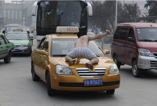 رجل صيني مخبول يعتلي سيارة أجرة مرتديا سرواله فقط خلال يوم نجح فيه فيه في تحطيم 20 سيارة بنفس الأسلوب حتى تم القبض عليه
