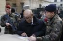French Defence Minister Le Drian listens to a soldier who explains a security mission the day before New Year's eve celebrations in Paris