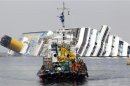 A boat with rescue workers sails in front of capsized cruise liner Costa Concordia near the harbour of Giglio Porto