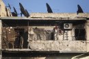 A bicycle hangs on a wall of a balcony of a damaged building in Aleppo's Karm al-Jabal district