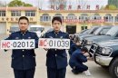 Officers of China's navy pose for photographs with the new and old military car licence plates, in Qinhuangdao