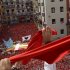 Revellers on the town hall balcony hold up red scarves during the start of the San Fermin Festival in Pamplona