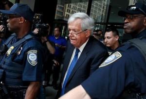 Former U.S. House of Representatives Speaker Dennis Hastert is surrounded by officers as he leaves federal court after pleading not guilty to federal charges of trying to hide large cash transactions and lying to the FBI in Chicago
