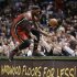 Miami Heat's LeBron James jumps onto a table while trying to save a ball going out of bounds against the Milwaukee Bucks in the second half of an NBA basketball game Friday, March, 15, 2013, in Milwaukee. (AP Photo/Jeffrey Phelps)