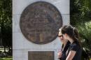 Women walk past a replica of a one drachma coin in Athens