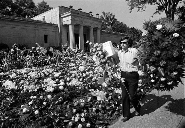 FILE - In this Aug. 18, 1977 file photo, a florist adds more floral arrangements to the overflowing collection of flowers that cover the ground at the mausoleum where singer Elvis Presley will be entombed during funeral services today in Memphis, Tenn. Celebrity auctioneer Darren Julien says the crypt inside the granite and marble mausoleum where Presley was originally entombed at the Forest Hill Cemetery in Memphis, Tenn., will be part of his "Music Icons" auction on June 23 and 24, 2012, in Beverly Hills, Calif. (AP Photo, File)
