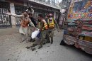 Rescue workers carry a dead body away from site of blast at University Road in Peshawar