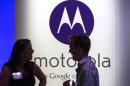 A man and woman laugh in front of a Motorola logo at a launch event for Motorola's new Moto X phone in New York