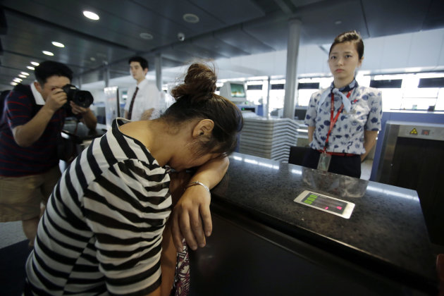 FILE - In this July 8, 2013 file photo, an unidentified family member of one of two Chinese students killed in a crash of an Asiana Airlines' plane on Saturday, cries at the airline's counter as she and other family members check in for a flight to San Francisco, at Pudong International Airport in Shanghai, China. In the first investigation of its kind, federal transportation officials are reviewing whether Asiana Airlines failed to meet legal obligations to help the families of passengers after one of its planes crashed at San Francisco International Airport, killing three people. Under U.S. law, Asiana was required to provide a range of services to family members of the 291 passengers, from the prompt posting of a toll-free number to gather and distribute information, to providing transportation and lodging so family members can comfort injured loved ones. (AP Photo/Eugene Hoshiko, File)