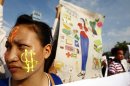 A Cambodian garment factory worker, left, is her face painted with the U.S. currency sign as she joins a rally on May Day in Phnom Penh, Cambodia, Wednesday, May 1, 2013. They demand the government an increase in wages and better working condition. (AP Photo/Heng Sinith)