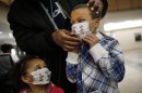 FILE - In this Wednesday, Jan. 9, 2013 file photo, Damien Dancy puts masks on his children Damaya, 3, left, and Damien, 7, at Sentara Princess Anne Hospital in Virginia Beach, Va., as hospitals in Hampton Roads are urging patients and visitors to wear a mask at their facilities to help stop the spread of the flu. Health officials say nine more deaths of children from the flu have been reported, bringing the total this flu season to 29. In a typical season, about 100 children die of the flu, so it is not known whether this year will be better or worse than usual. The Centers for Disease Control and Prevention says half of confirmed flu cases so far are in people 65 and older. (AP Photo/The Virginian-Pilot, Stephen M. Katz, File)