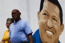 People walk past a mural of Venezuela's President Hugo Chavez in Caracas