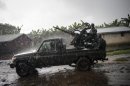 A truck of the Armed Forces of the Democratic Republic of the Congo leaves a firing position through a village in Jomba