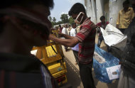 Workers at a school-turned-morgue place the body of a victim from last week's collapse of a garment factory building into a coffin, Saturday, May 4, 2013 in Savar, near Dhaka, Bangladesh. The death toll in the accident rose to more than 530 on Saturday, a day after the country's finance minister downplayed the impact of the disaster on the garment industry, saying he didn't think it was "really serious." (AP Photo/Wong Maye-E)