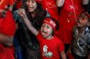 Supporters celebrate as they watch official results from the Union Election Commission on an LED screen in front of the National League for Democracy Party (NLD) head office in Yangon