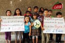 In this citizen journalism image provided by the Local Comity of Arbeen which has been authenticated based on its contents and other AP reporting, Syrian children hold signs as they pose for a photograph during a demonstration in Arbeen town, suburb of Damascus, Syria, Monday, Sept. 2, 2013. More than 100,000 Syrians have been killed since an uprising against Syrian President Bashar Assad erupted in 2011. (AP Photo/Local Comity of Arbeen)