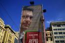 A worker hangs a banner with an image of former Greek prime minister and leader of leftist Syriza party Alexis Tsipras at the party's pre-election kiosk in Athens
