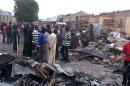 People stand at the scene on March 2, 2014, a day after two explosions rocked killing at leat 35 people in Nigeria's restless northeastern city of Maiduguri, a stronghold of Boko Haram Islamists