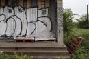 A homeless person sleeps under a blanket on the porch of a shuttered public school covered with graffiti in a once vibrant southwest neighborhood in Detroit,