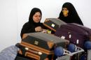 Women check their luggage after arriving on a flight from Dubai on Emirates Flight 203 at John F. Kennedy International Airport in Queens, New York, U.S.