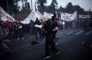 Protesters hold up banners as others clash with Greek riot police during a demonstration against the latest reform measures demanded by creditors, in Athens on May 8, 2016
