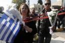 People holding flowers and a Greek flag stand near the local offices of far-right Golden Dawn party, following last night's shooting, in a northern suburb of Athens