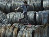 A labourer walks on coils of steel wire at a steel market in Shenyang