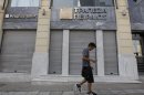 Man walks outside of closed Piraeus bank branch in central Athens