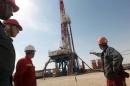 Gazprom employees look at a drilling platform at an oilfield near the Badra, south of Baghdad, on October 18, 2012