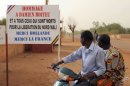 Dos hombres pasan frente a un cartel contra la intervención francesa en Malí, este 30 de enero en Gao