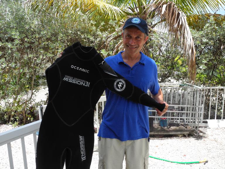 Fabien Cousteau, grandson of French oceanographer Jacques Cousteau, holds a scuba suit during an interview with AFP in Islamorada, Florida, on May 31, 2014