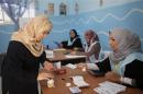 A woman dips her finger in a bottle of ink before voting in the municipal election at a polling station in Benghazi