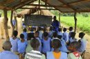 A teacher conducts a lesson under a makeshift classroom at a relief centre for flood victims at St. Boniface primary school in Idah